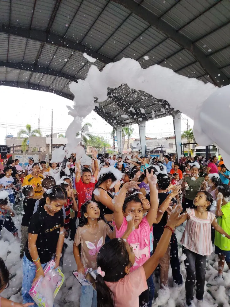 Niños celebrando bajo el chorro del cañón de espuma en una cancha cubierta